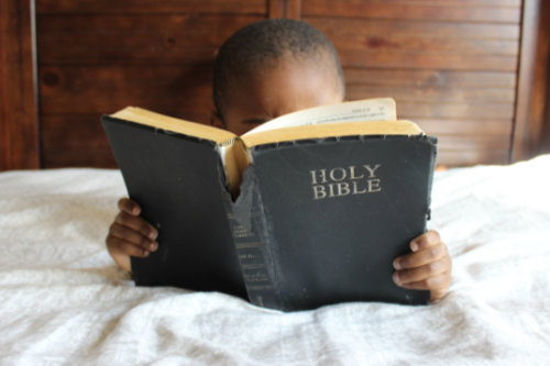 Photo of boy with Bible as big as him